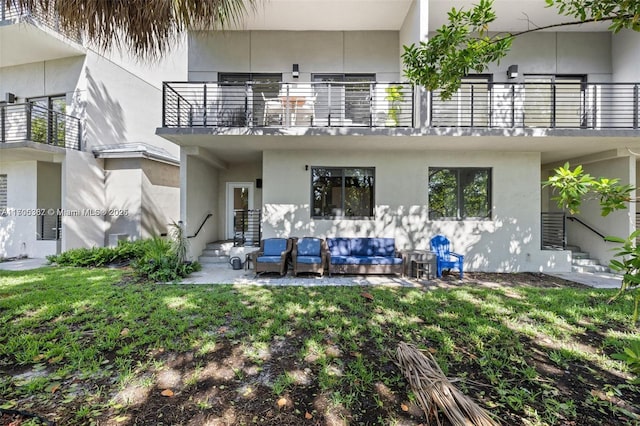 rear view of house with a balcony, a yard, and an outdoor hangout area