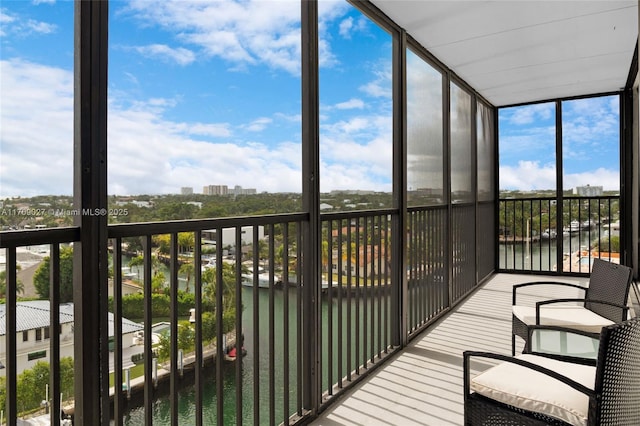 unfurnished sunroom with a wealth of natural light, a water view, and a view of city