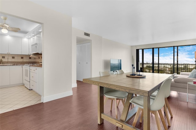 dining area featuring floor to ceiling windows, visible vents, light wood-style floors, ceiling fan, and baseboards