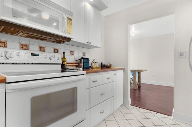 kitchen featuring white appliances, tasteful backsplash, light tile patterned floors, baseboards, and white cabinetry