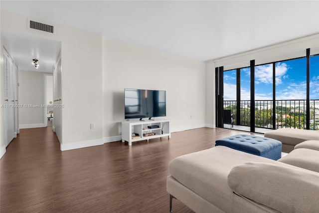 living room featuring dark wood-style floors, baseboards, visible vents, and floor to ceiling windows