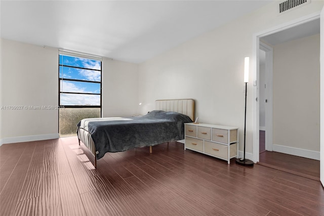 bedroom featuring a wall of windows, visible vents, baseboards, and wood finished floors