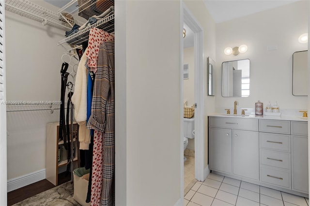 full bath with a spacious closet, toilet, vanity, baseboards, and tile patterned floors