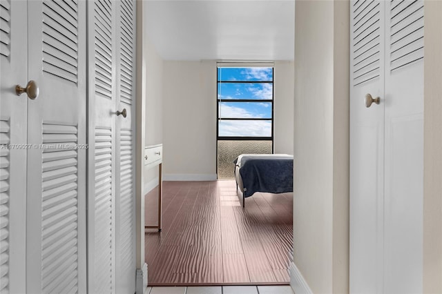 hall with baseboards, floor to ceiling windows, and wood finished floors