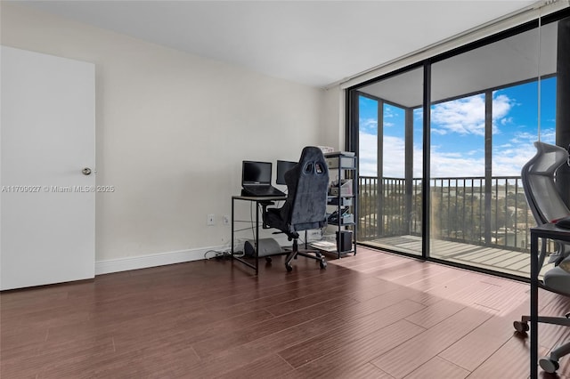 home office featuring baseboards, a wall of windows, and wood finished floors