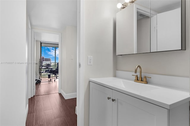 bathroom with a wall of windows, wood finished floors, vanity, and baseboards