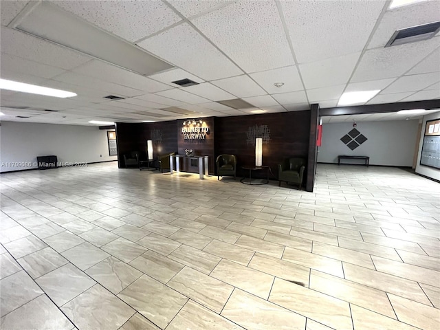 basement with a paneled ceiling and wood walls