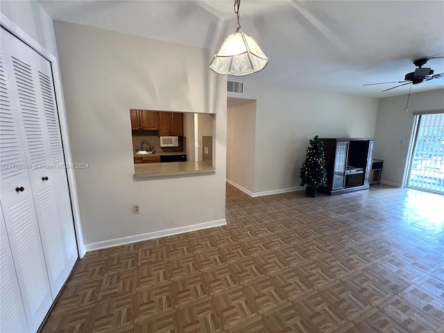 unfurnished living room with ceiling fan, dark parquet flooring, and sink