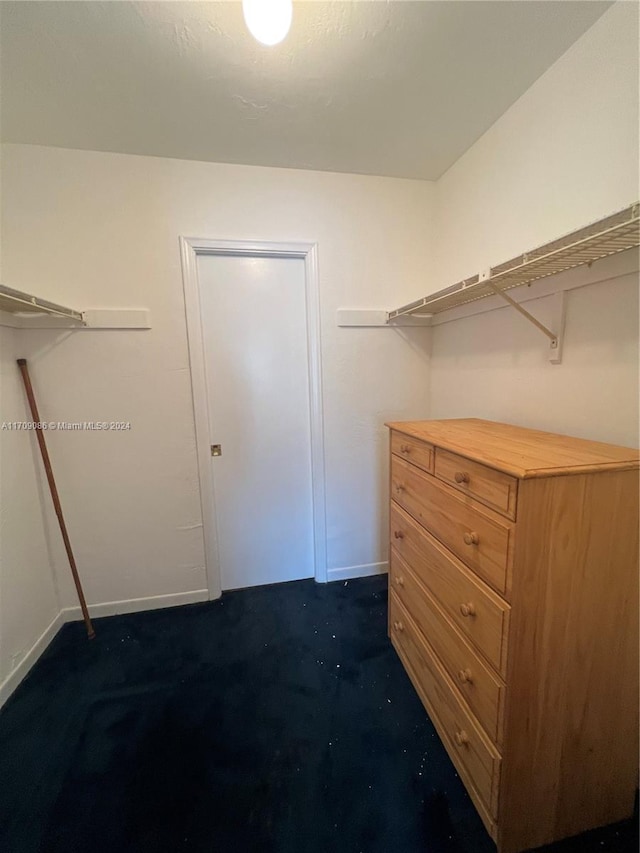 walk in closet featuring dark colored carpet