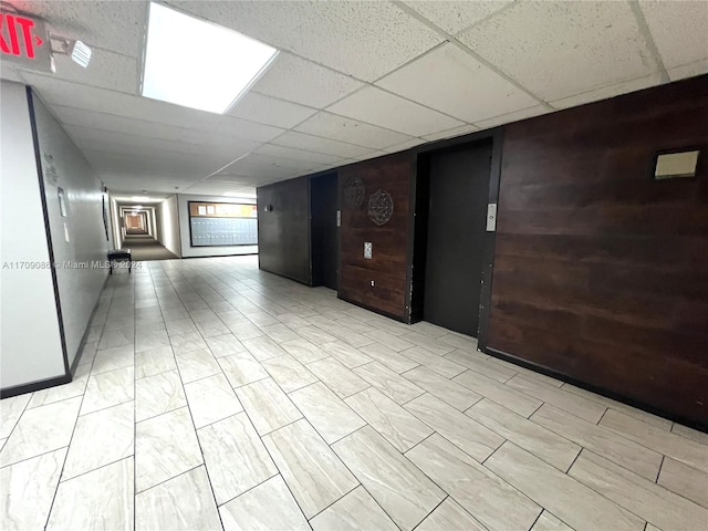 spare room with a drop ceiling and wooden walls