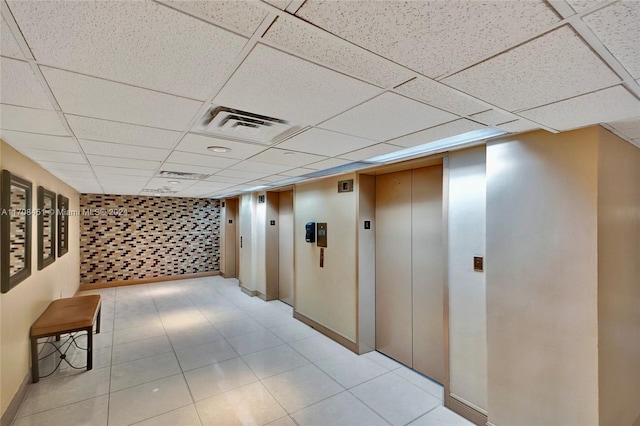 hall featuring a paneled ceiling and elevator