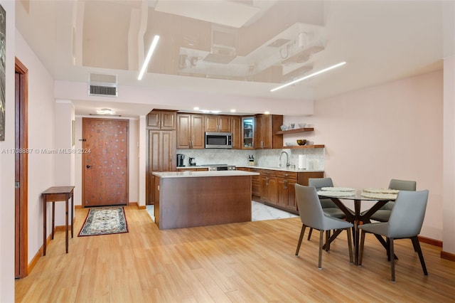 kitchen featuring appliances with stainless steel finishes, backsplash, sink, a center island, and light hardwood / wood-style floors