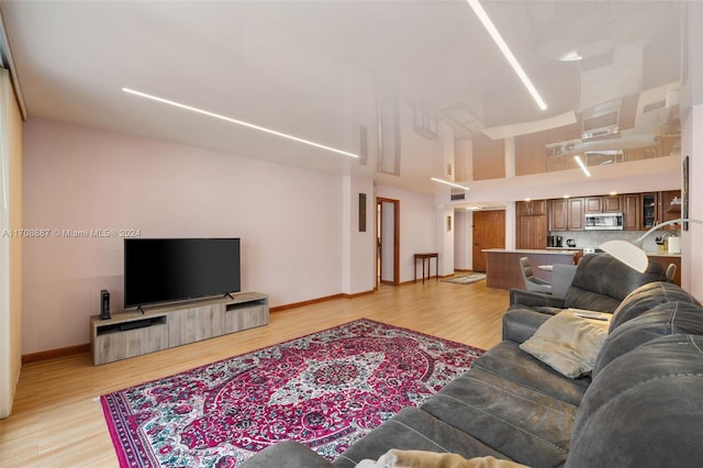 living room with light wood-type flooring and a high ceiling