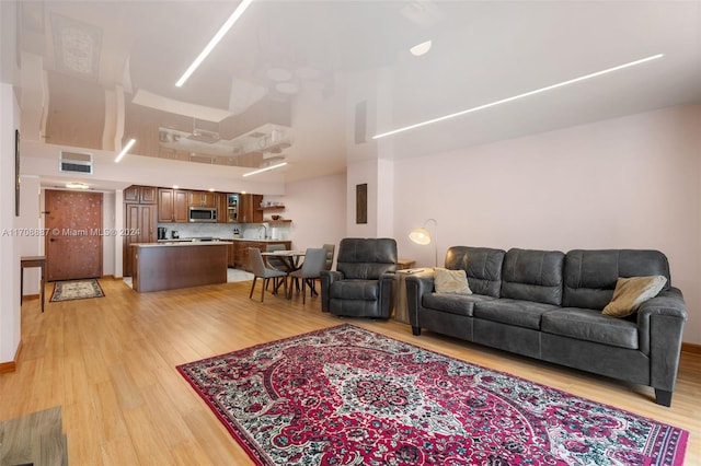 living room featuring light hardwood / wood-style flooring, a towering ceiling, and sink