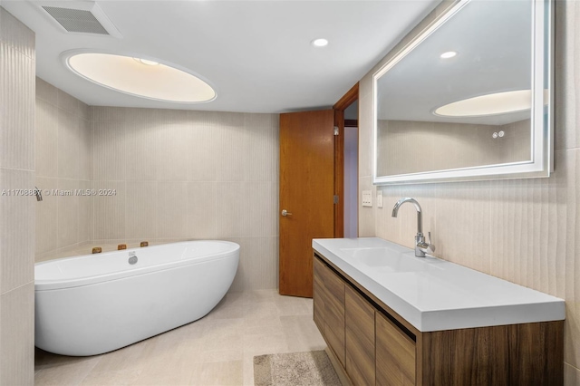 bathroom with tile patterned floors, a washtub, vanity, and tile walls