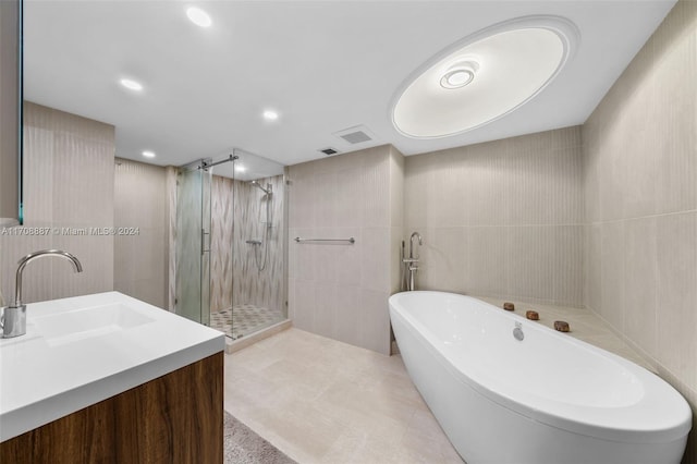 bathroom featuring vanity, separate shower and tub, and tile walls