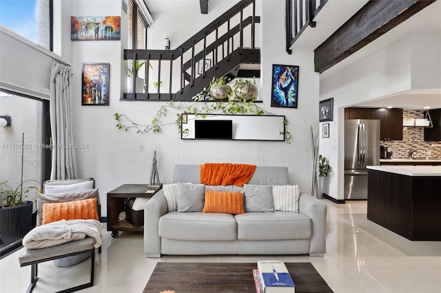 living room with beamed ceiling, a towering ceiling, and light tile patterned floors