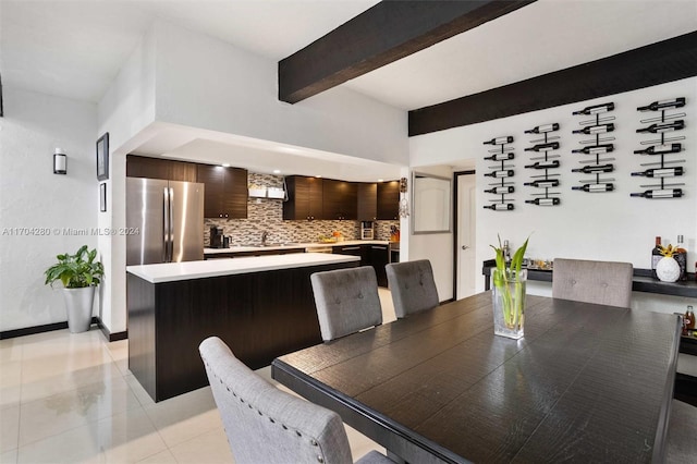 tiled dining area featuring sink and beamed ceiling