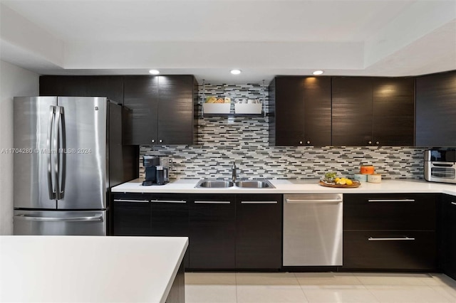 kitchen with sink, light tile patterned floors, appliances with stainless steel finishes, tasteful backsplash, and dark brown cabinets