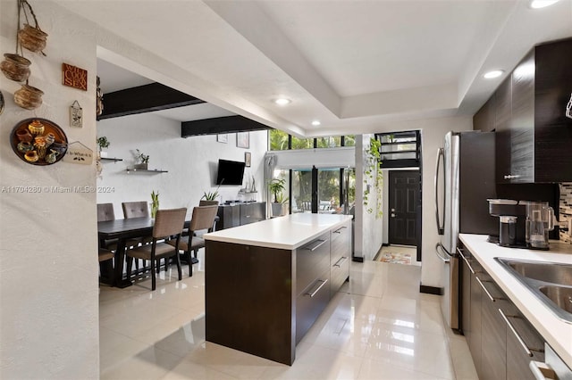 kitchen with dark brown cabinetry, a center island, french doors, a tray ceiling, and light tile patterned floors