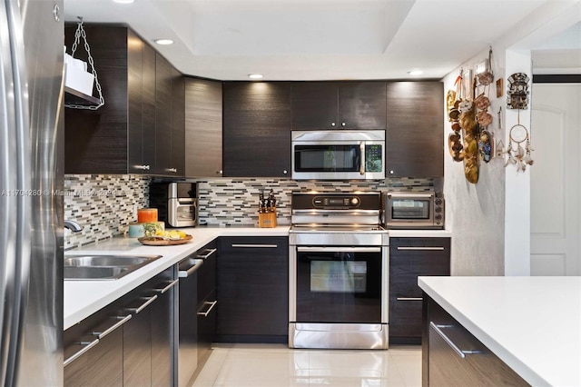 kitchen featuring decorative backsplash, dark brown cabinetry, sink, and appliances with stainless steel finishes