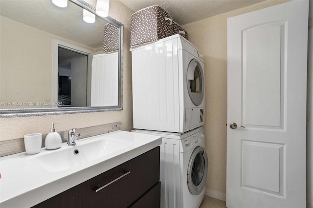 laundry room featuring a textured ceiling, stacked washer and clothes dryer, and sink