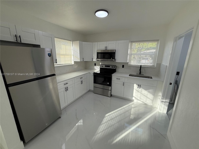 kitchen featuring white cabinetry, plenty of natural light, stainless steel appliances, and sink