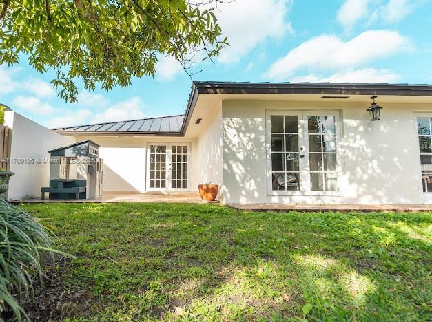 rear view of property with french doors and a yard