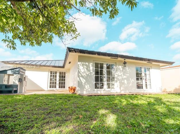 back of house featuring a lawn and french doors