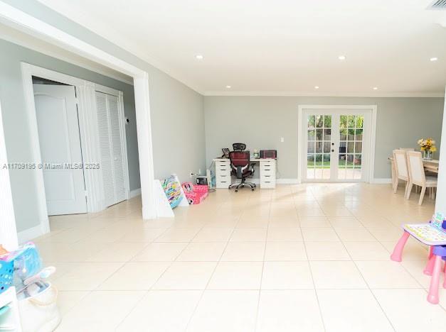 rec room with french doors, crown molding, and light tile patterned flooring