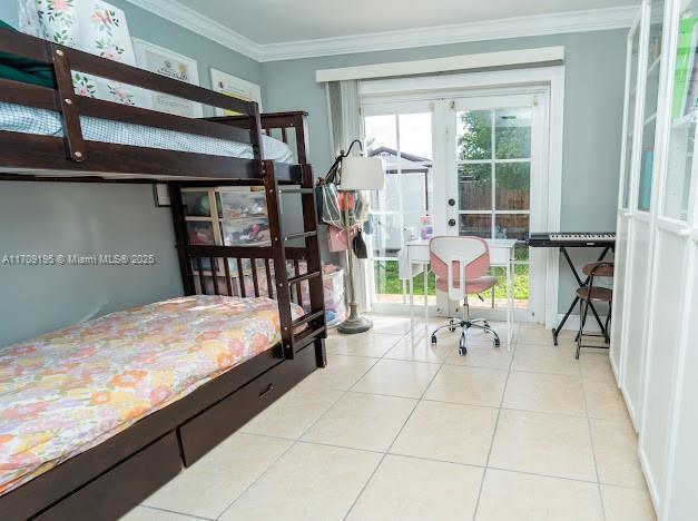 tiled bedroom with crown molding and french doors