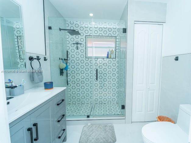 bathroom featuring vanity, toilet, and a shower with shower door