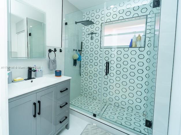 bathroom with vanity, a shower with door, and tile walls