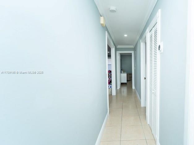 hall with crown molding and light tile patterned floors