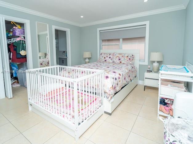 bedroom with crown molding, a spacious closet, and light tile patterned flooring