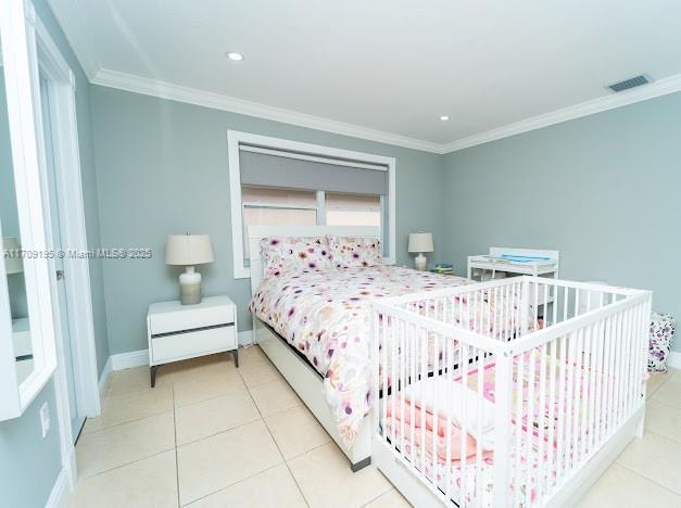 bedroom featuring light tile patterned floors and ornamental molding