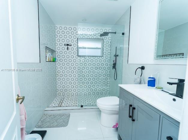 bathroom with vanity, toilet, and a tile shower