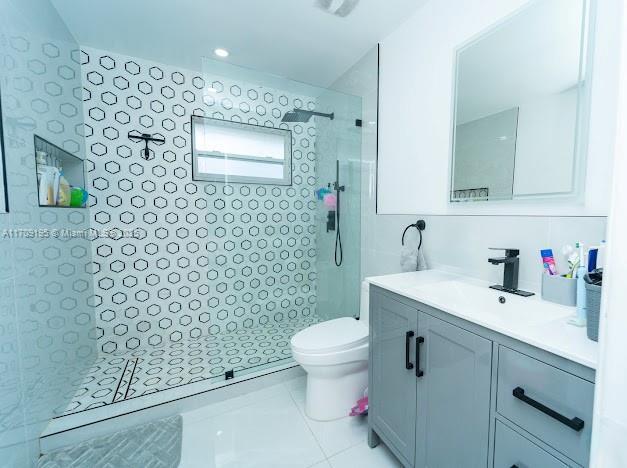 bathroom featuring tiled shower, vanity, and toilet