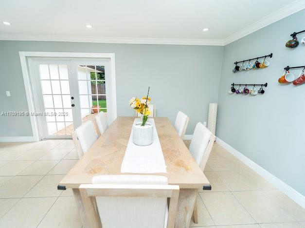 dining area with crown molding, light tile patterned flooring, and french doors