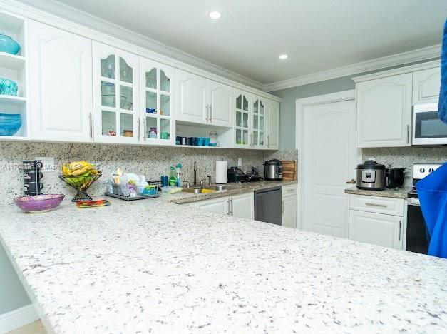 kitchen with dishwasher, ornamental molding, white cabinets, and decorative backsplash