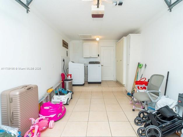 clothes washing area with light tile patterned floors, cabinets, and independent washer and dryer