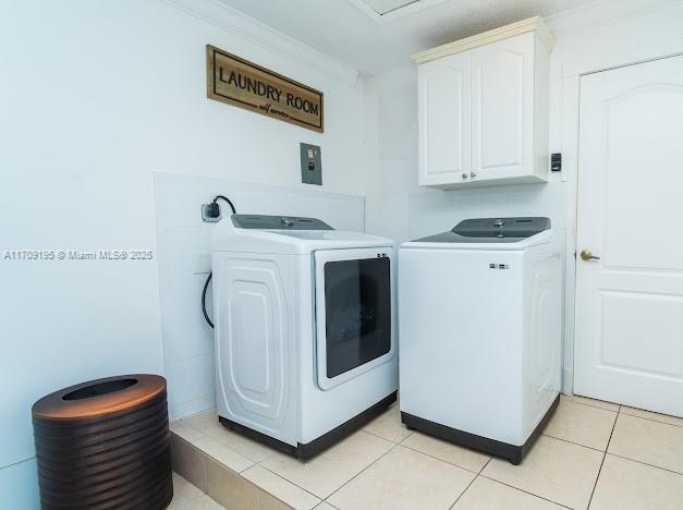 clothes washing area featuring light tile patterned flooring, cabinets, ornamental molding, and separate washer and dryer