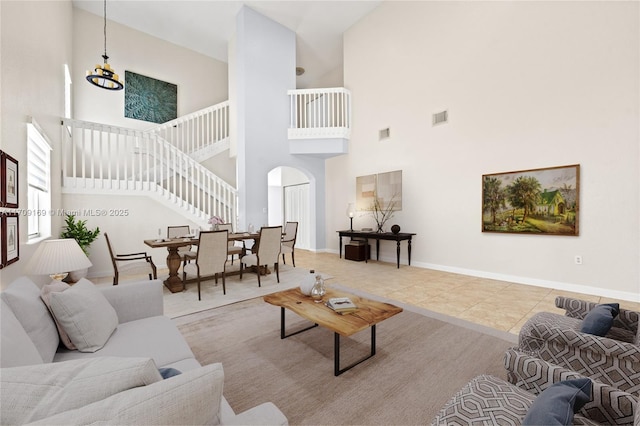 tiled living room featuring a towering ceiling and a notable chandelier