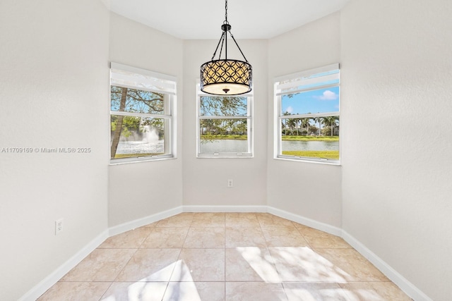 empty room with plenty of natural light, light tile patterned floors, and a water view