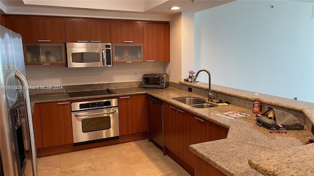 kitchen with kitchen peninsula, light stone countertops, sink, and appliances with stainless steel finishes