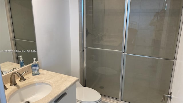 bathroom featuring vanity, an enclosed shower, and toilet