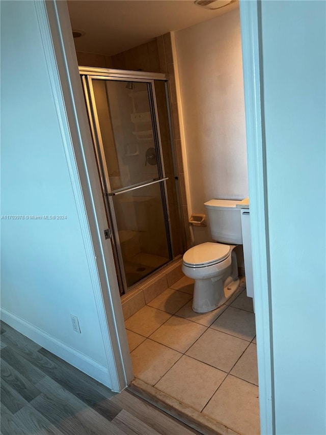 bathroom featuring toilet and a shower with door