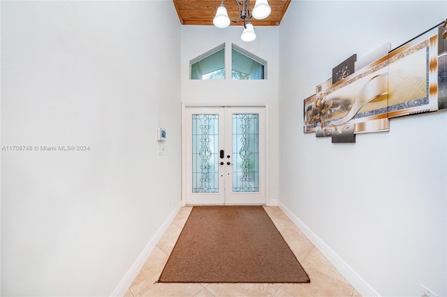 tiled entryway with a chandelier, wooden ceiling, a high ceiling, and french doors