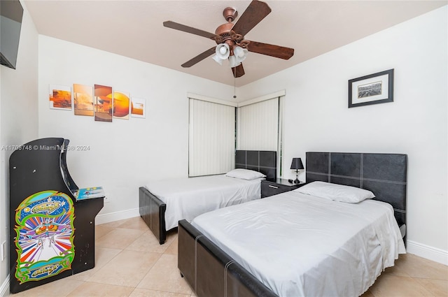 tiled bedroom with ceiling fan and a closet