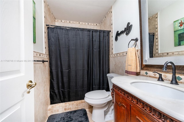 bathroom with vanity, tile patterned flooring, a shower with shower curtain, toilet, and tile walls